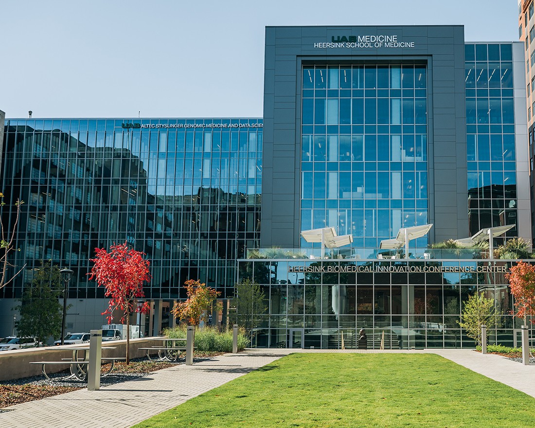 Small trees in orange fall color are on the Kracke Plaza green space outside of Heersink Biomedical Innovation Conference Center at Altec Styslinger Genomic Medicine and Data Sciences building.