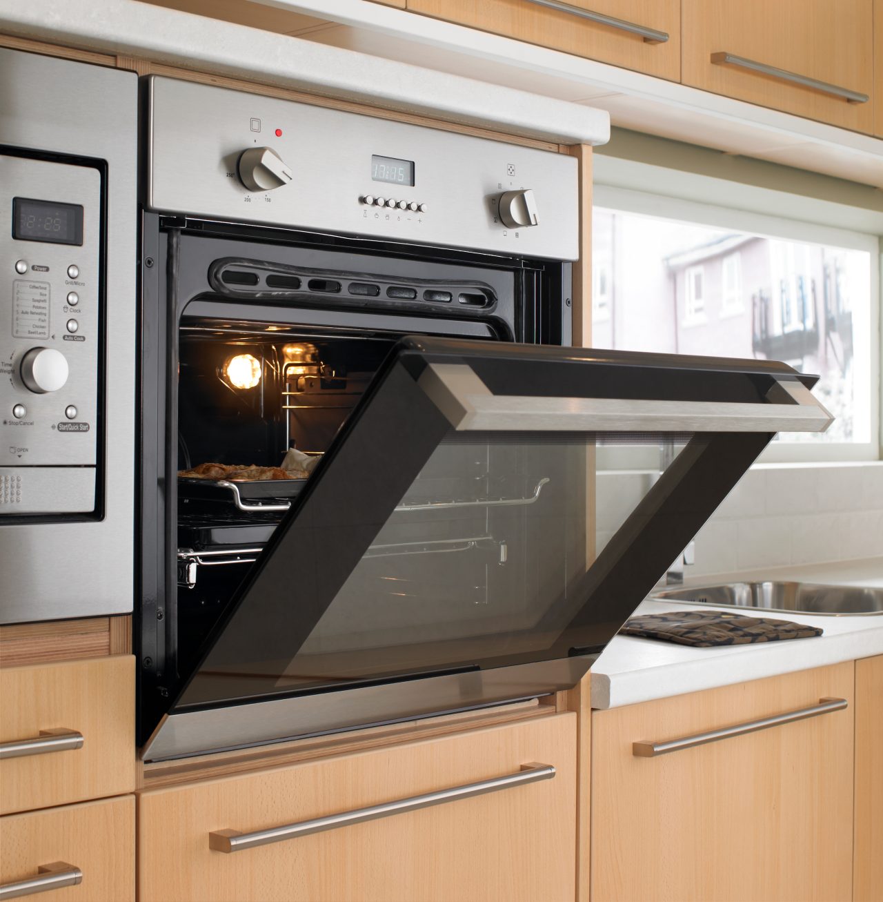 Oven door open in kitchen looking at appetizing pork joint cooking